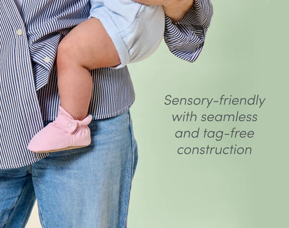 Mom holding baby wearing sensory-friendly Ten Little Everyday Baby Booties with seamless and tag-free construction - Soft Pink. Available at www.tenlittle.com